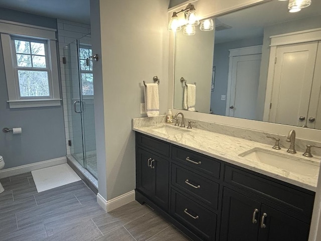 bathroom featuring a sink, toilet, a shower stall, and double vanity