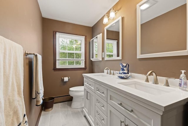 bathroom with a baseboard heating unit, toilet, and double vanity