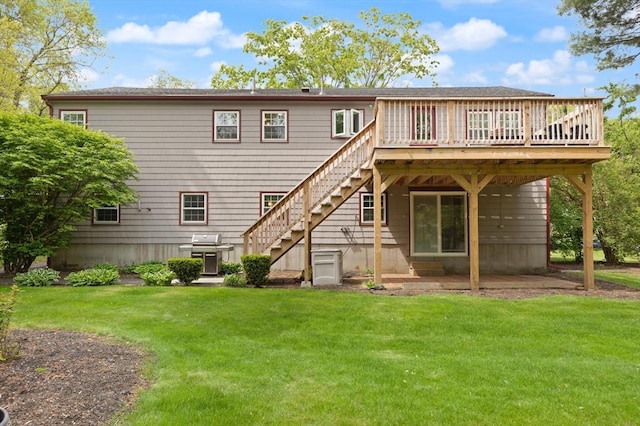 rear view of property featuring a lawn, stairway, a wooden deck, and a patio