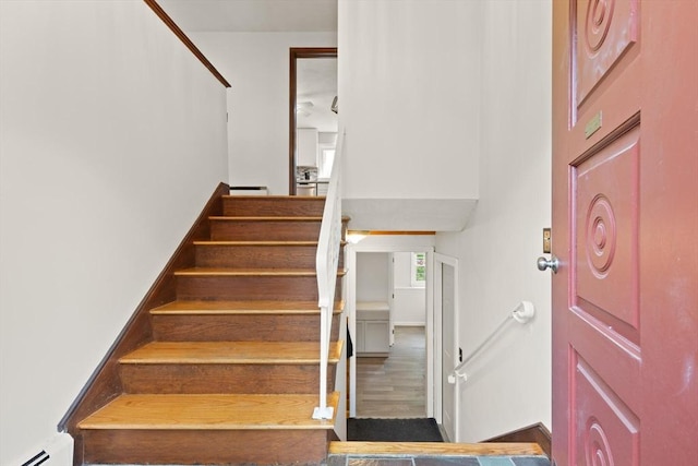 foyer featuring a baseboard radiator, stairway, and wood finished floors