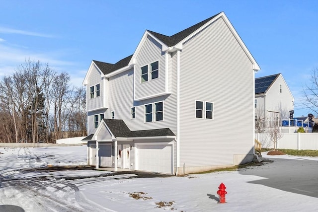 snow covered rear of property with a garage