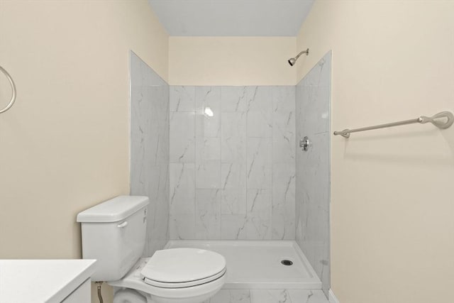 bathroom with toilet, tiled shower, and vanity