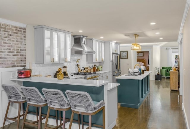 kitchen featuring a kitchen bar, kitchen peninsula, and wall chimney range hood