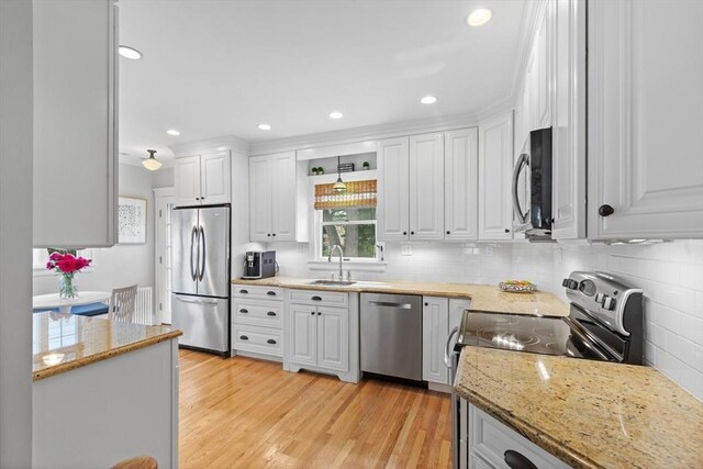 32 Oneida Rd, Winchester, MA 01890 - kitchen with appliances with stainless steel finishes, white cabinetry, tasteful backsplash, light wood-style flooring, and recessed lighting