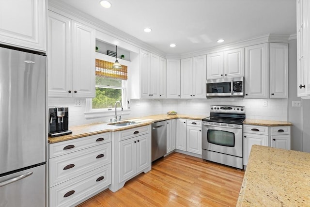 32 Oneida Rd, Winchester, MA 01890 - kitchen featuring appliances with stainless steel finishes, white cabinetry, light wood-type flooring, backsplash, and recessed lighting