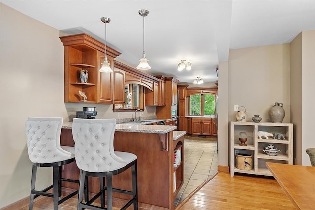 421 Legate Hill Rd, Charlemont, MA 01339 - kitchen featuring open shelves, a kitchen breakfast bar, brown cabinets, a peninsula, and hanging light fixtures