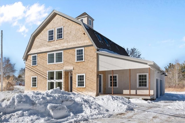 snow covered house featuring a gambrel roof