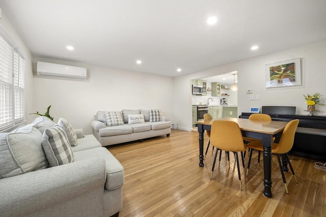 living room featuring a wall mounted AC, light wood-style flooring, recessed lighting, and baseboards