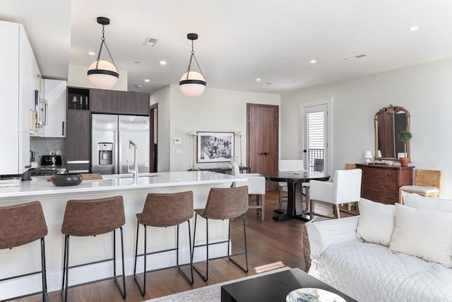 kitchen with stainless steel fridge, open floor plan, a peninsula, light countertops, and a kitchen bar