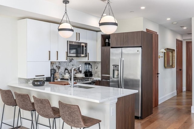 kitchen featuring stainless steel appliances, tasteful backsplash, modern cabinets, a peninsula, and a kitchen bar