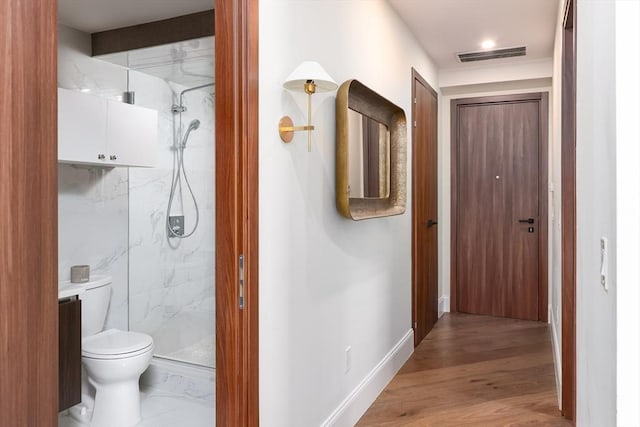 corridor featuring wood finished floors, visible vents, and baseboards