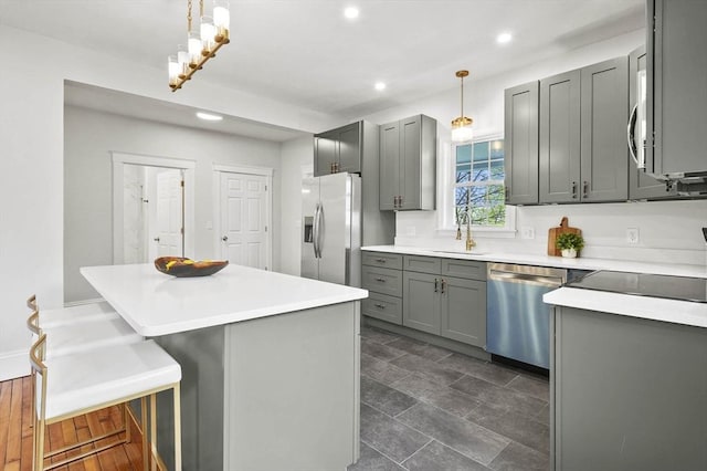 kitchen featuring appliances with stainless steel finishes, gray cabinets, a sink, recessed lighting, and light countertops