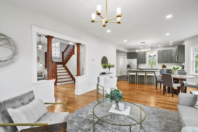 living area featuring a chandelier, light wood finished floors, recessed lighting, and stairs