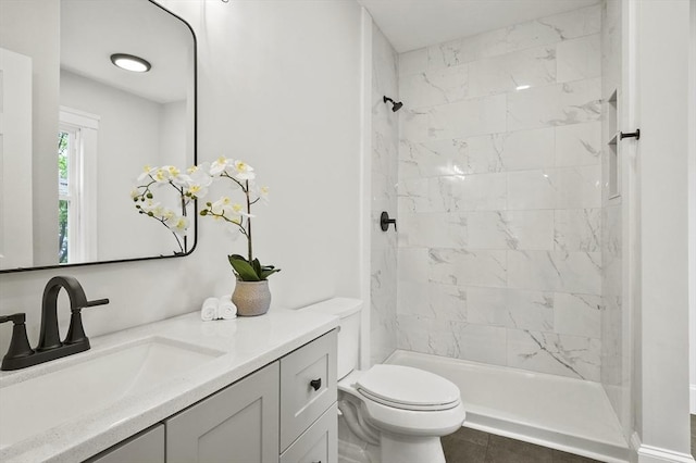 bathroom featuring toilet, tiled shower, and vanity