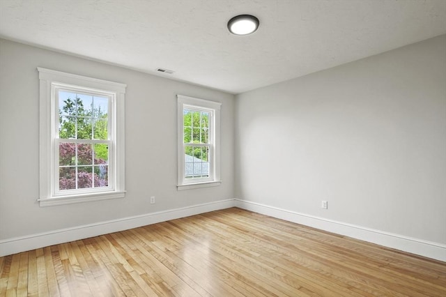 spare room with baseboards and light wood-type flooring
