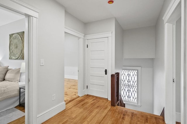 corridor featuring an upstairs landing, wood finished floors, and baseboards