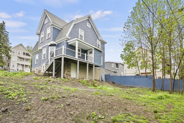 rear view of property with fence, stairs, a gambrel roof, and a deck