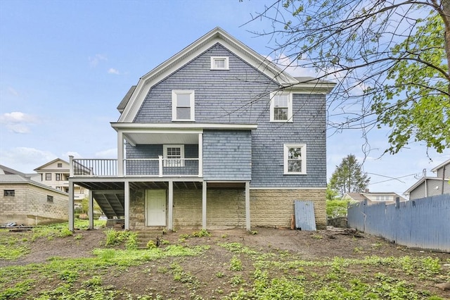 rear view of house with a deck, stairs, fence, and stone siding