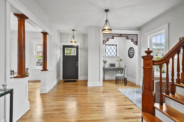 entrance foyer featuring ornate columns, light wood-style floors, baseboards, and stairway
