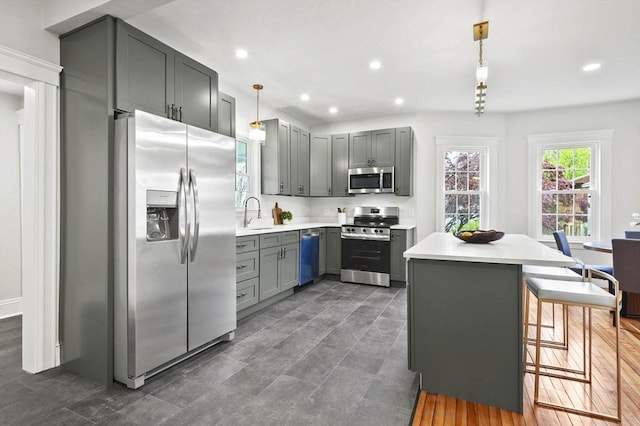 kitchen featuring stainless steel appliances, light countertops, gray cabinetry, a sink, and recessed lighting