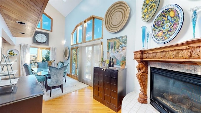 interior space featuring a glass covered fireplace, light wood-style flooring, and high vaulted ceiling