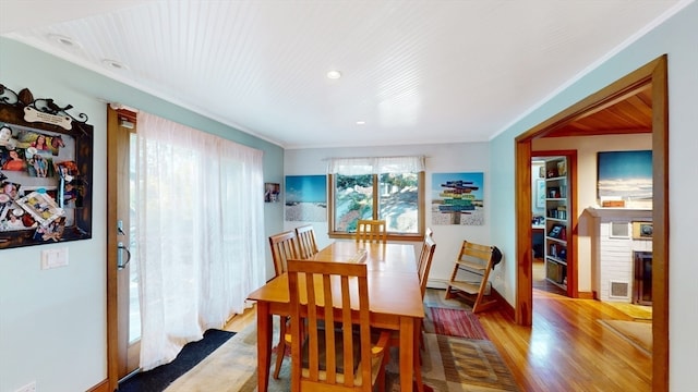 dining room with light wood-type flooring and crown molding