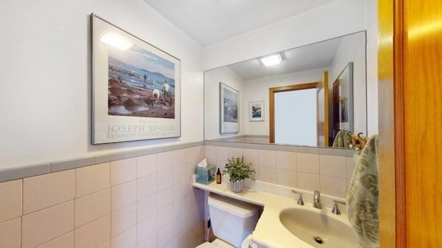 bathroom with a wainscoted wall, tile walls, and vanity