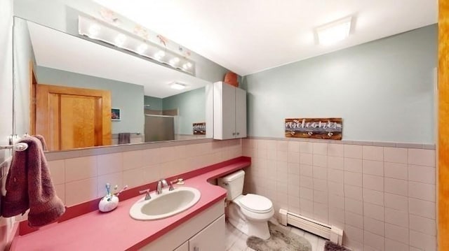 bathroom featuring vanity, a shower stall, a baseboard heating unit, tile walls, and toilet