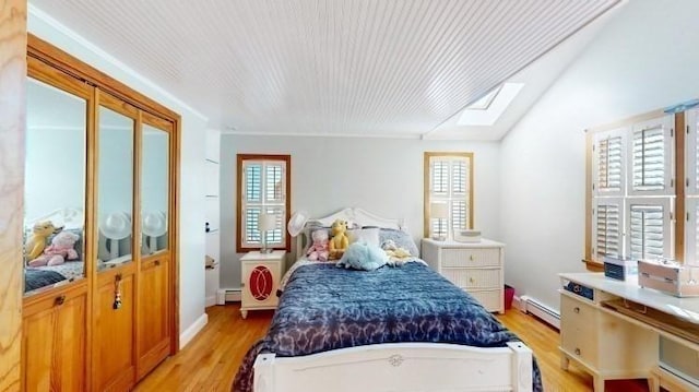 bedroom with multiple windows, a baseboard heating unit, light wood-type flooring, and a baseboard radiator