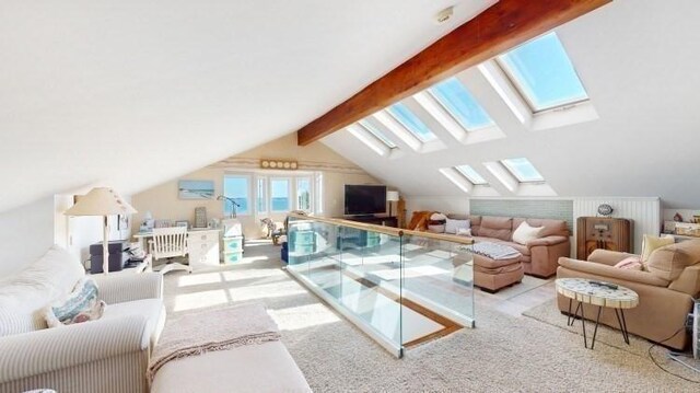 living room featuring vaulted ceiling with skylight and light carpet