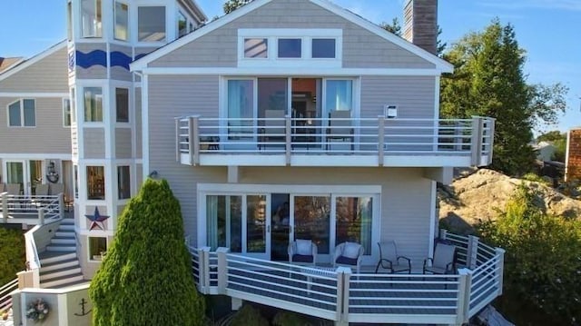 rear view of house with stairway, a balcony, and a chimney