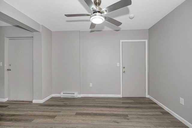 empty room with ceiling fan, baseboard heating, and wood-type flooring