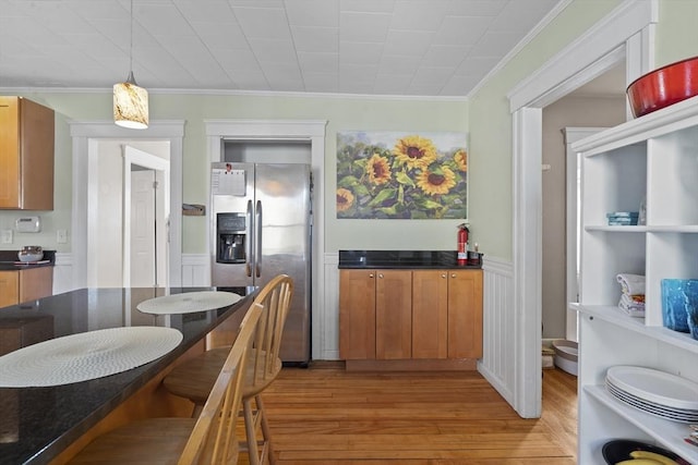 kitchen with ornamental molding, decorative light fixtures, stainless steel fridge with ice dispenser, and light wood-type flooring