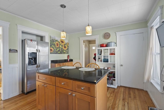 kitchen with hanging light fixtures, ornamental molding, stainless steel fridge, a kitchen island, and light hardwood / wood-style floors