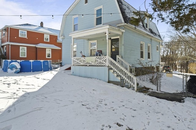 snow covered house featuring a porch