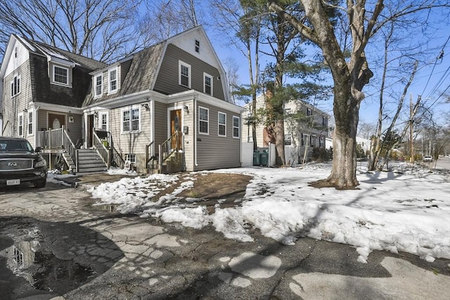 view of snowy exterior featuring roof with shingles and a gambrel roof