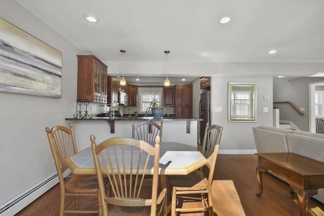 dining area featuring a baseboard radiator, recessed lighting, dark wood-type flooring, baseboards, and stairs