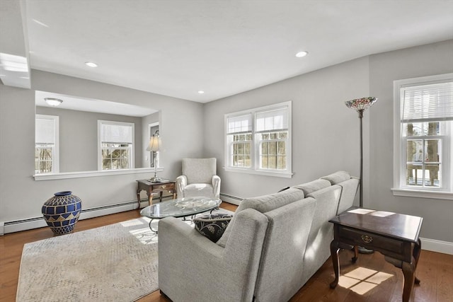 living room featuring a baseboard heating unit, baseboards, wood finished floors, and recessed lighting