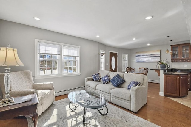 living room featuring light wood-style flooring, a baseboard heating unit, and recessed lighting