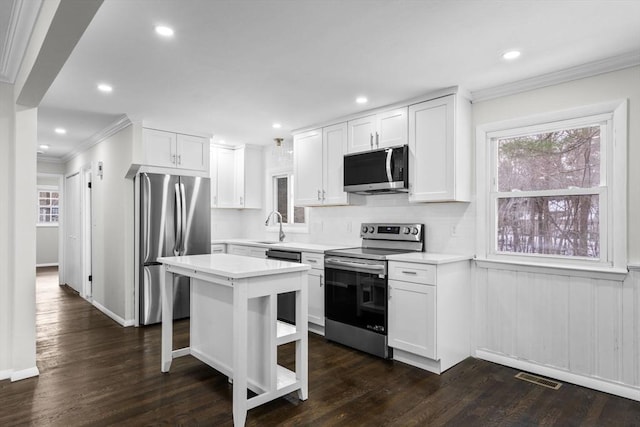 kitchen with white cabinetry, appliances with stainless steel finishes, dark hardwood / wood-style floors, and a center island