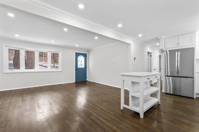 kitchen with white cabinets, crown molding, stainless steel fridge, and dark hardwood / wood-style flooring