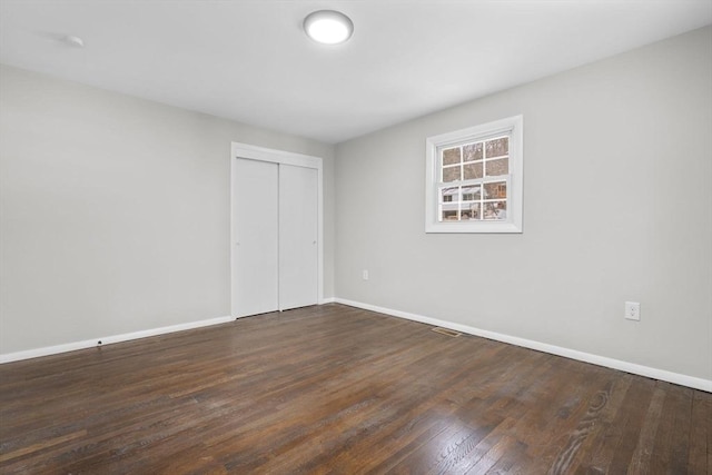 unfurnished bedroom featuring dark wood-type flooring and a closet