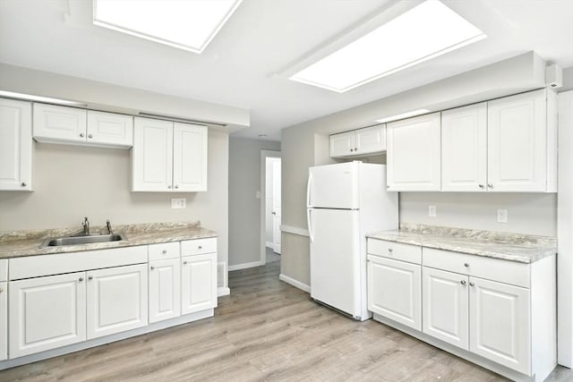 12-14 Kendall St, Springfield, MA 01104 - kitchen with a sink, freestanding refrigerator, light countertops, white cabinetry, and light wood-type flooring