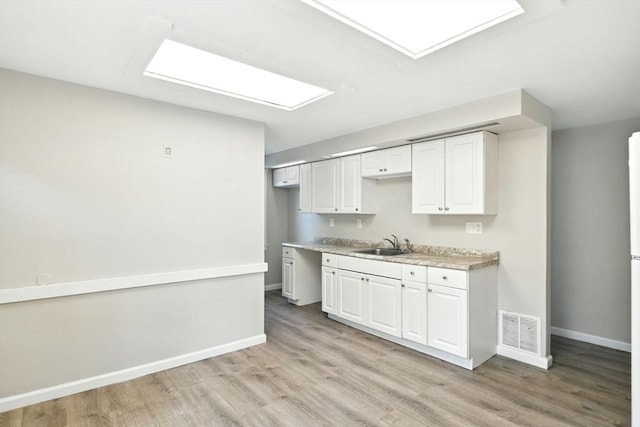 12-14 Kendall St, Springfield, MA 01104 - kitchen with a sink, light wood finished floors, baseboards, light countertops, and white cabinets