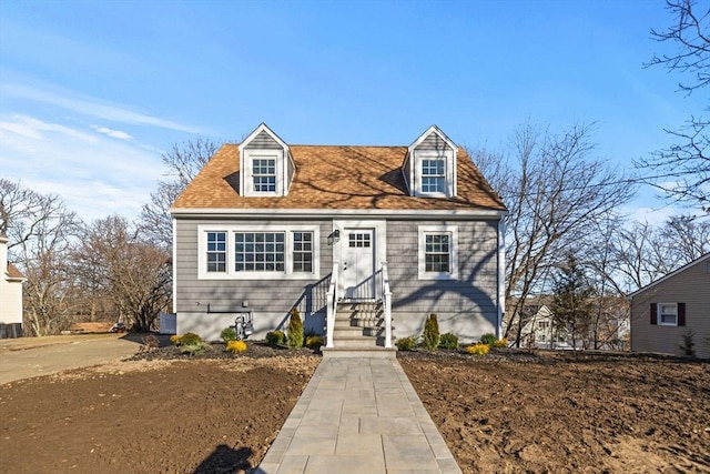 new england style home featuring roof with shingles