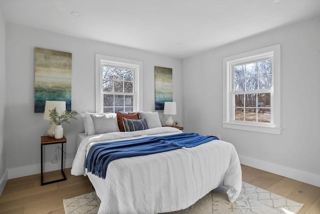 bedroom featuring baseboards, multiple windows, and wood finished floors