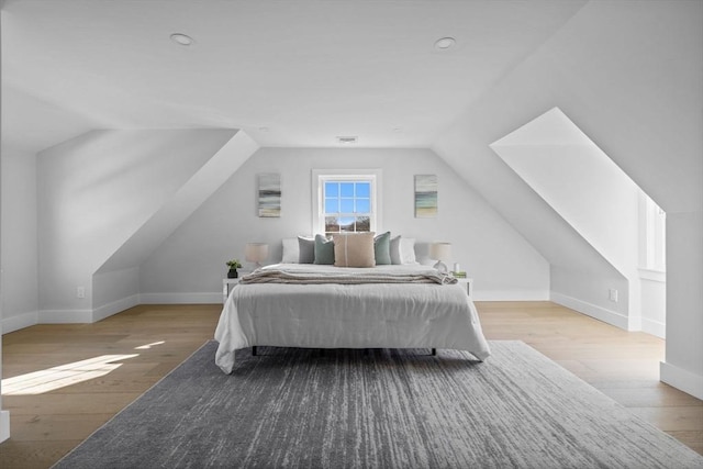 bedroom with vaulted ceiling, visible vents, baseboards, and wood-type flooring