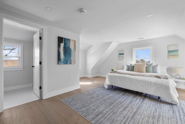 bedroom with multiple windows, lofted ceiling, and wood finished floors