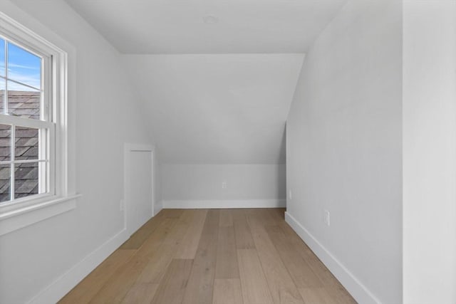 additional living space featuring baseboards, wood finished floors, and vaulted ceiling