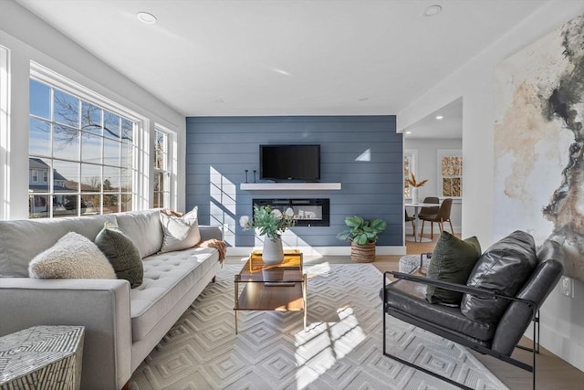 living area with a glass covered fireplace, recessed lighting, baseboards, and wood finished floors